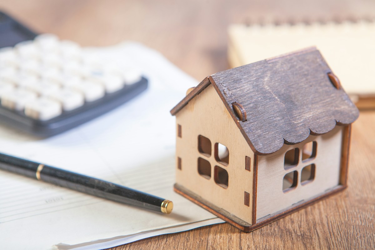 Modelwoning, rekenmachine en notitieblok voor het bepalen van een startbedrag